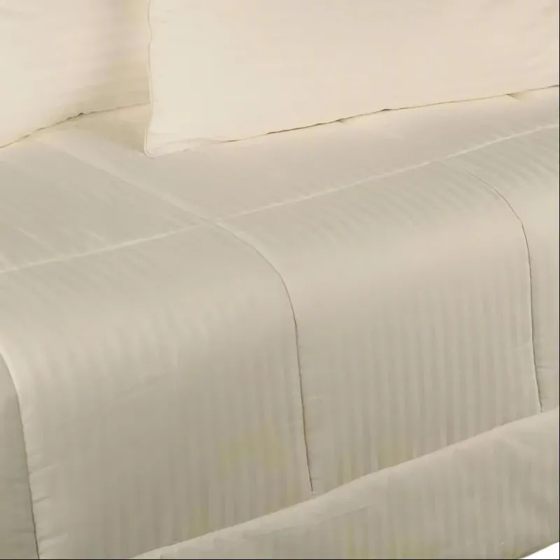 Kumi Kookoon ivory cotton comforter with tonal satin stripes on a made bed.