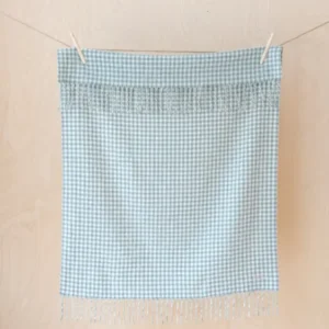 TBCo Lambswool Baby Blanket in sage and cream gingham pattern, hanging on a line showing fringed edges and soft texture