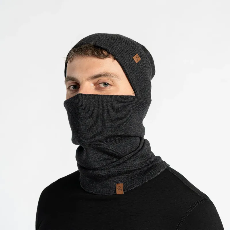 Person wearing a dark gray knit beanie and scarf set on a light gray background