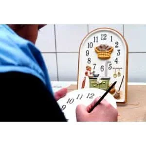 Handbemalte Wanduhr mit Teekannenmotiv, runde Ziffern und goldene Zeiger.