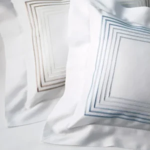Dea Milano white pillow shams with taupe and blue concentric square embroidery.