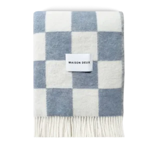 Denim blue and white checkerboard wool blanket folded with fringe detail