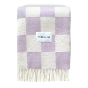 Lilac and white checkerboard wool blanket folded with fringe detail